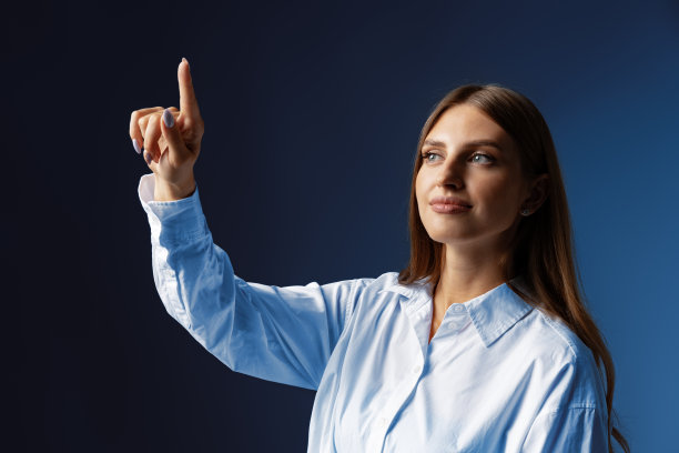 年轻的女企业家在灰色的工作室背景下触摸虚拟屏幕图片下载