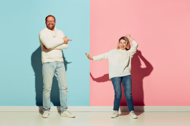 工作室拍摄的夫妇年轻有趣和快乐的男人和女人在蓝色和粉红色的背景上有孤立的乐趣。图片下载