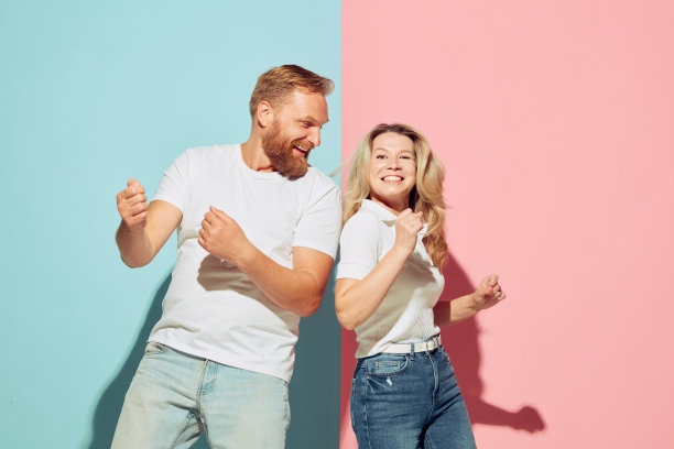 一对年轻的快乐的男人和女人跳舞，有乐趣孤立在蓝粉色的工作室背景。人的情感、青春、爱情和生活方式观念图片下载