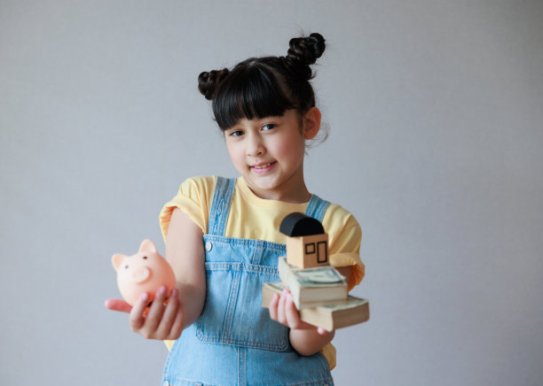 亚洲可爱女孩手握储蓄罐和家庭模型，存钱，规划未来理财。图片下载