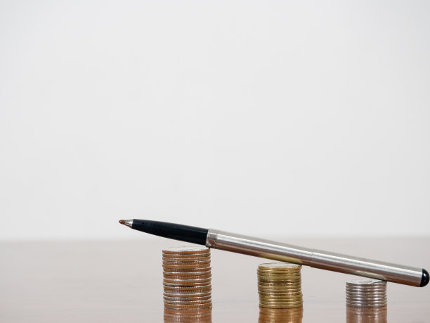 笔上的硬币在桌子上渐渐长大，白色的背景复制空间图片下载