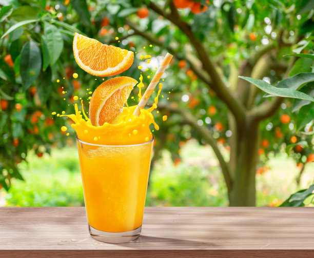 一杯橙汁，洒在木桌上。背景是模糊的果园。图片下载