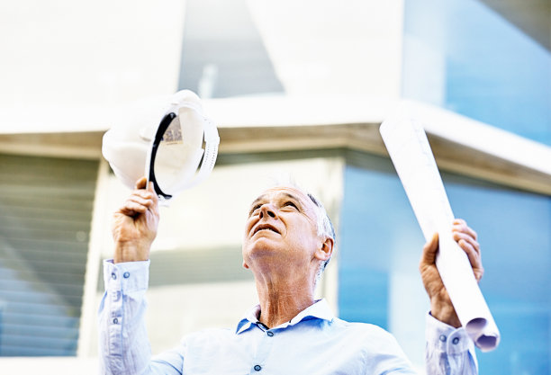 上面发生什么事了?建筑师、土木工程师或建筑老板手里拿着计划和安全帽，抬起头来图片下载