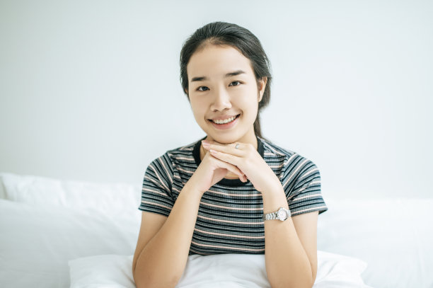 一个女人坐在那里，双手托着下巴，开心地笑着。图片下载