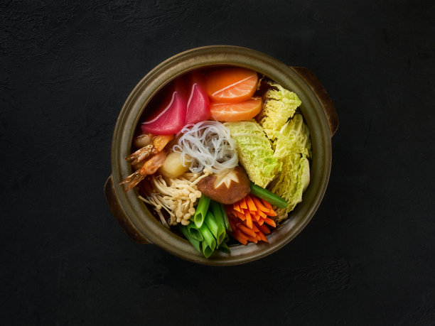 亚洲或日本风格的汤，面条，金枪鱼，鲑鱼，蘑菇和大葱特写在碗上的桌子。从上面的水平俯视图图片下载