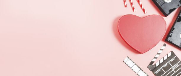 一个心形的盒子，有隔板，吸管和薄膜条躺在右边，粉红色的背景。图片下载