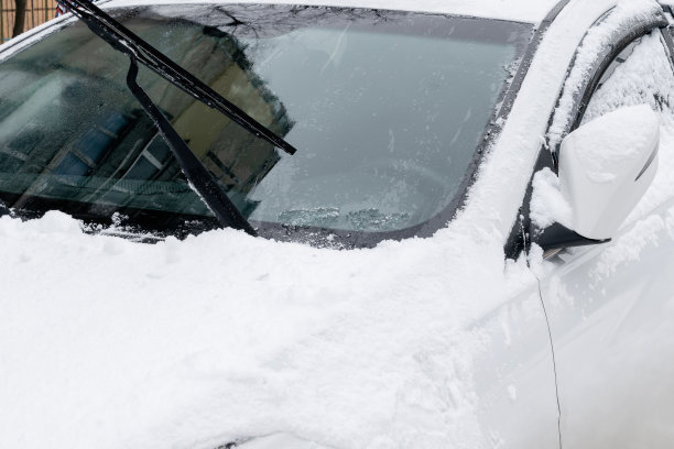 汽车挡风玻璃和引擎盖上有新鲜的冰雪层。冬天在暴风雪后清理汽车上的积雪图片下载