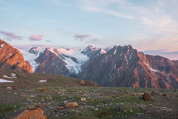 生动的高山景观，高高的雪山和巨大的冰川在日出的颜色。五颜六色的山景，阳光照射下的粉红色岩石和日出时的金色山脉。在海拔很高的清晨图片下载
