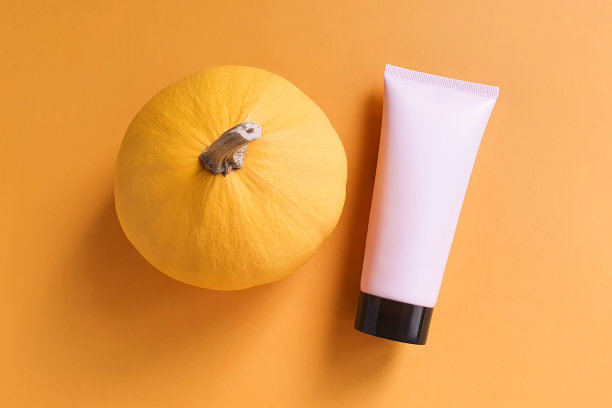 模型的粉红色挤压瓶化妆品管螺旋黑色帽和黄色南瓜在黄色背景。手霜，沐浴露，护肤品，洗发水，保湿霜。前顶视图，空白管，平铺设图片下载