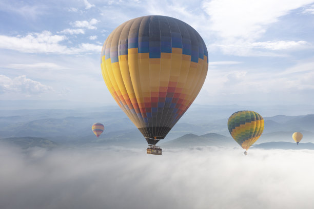 五颜六色的热气球在云层上空飞行。图片下载