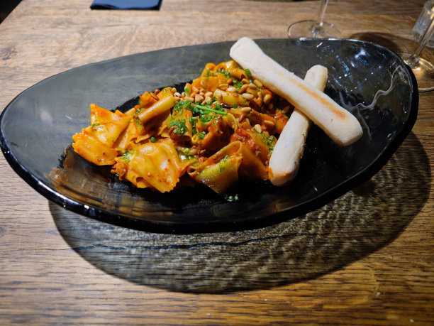 意大利肉酱面配意大利宽面条，配肉酱酱，肉酱酱由碎牛肉、香蒜酱、芝麻菜、帕达诺干酪和松子制成，放在餐厅餐桌上图片下载