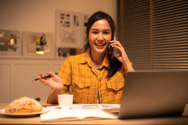 年轻漂亮的女人在黄色衬衫工作很晚从家里的客厅深夜加班。女商人在工作场所低头看电脑。图片下载