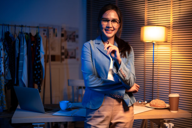 年轻漂亮的女人在黄色衬衫工作很晚从家里的客厅深夜加班。女商人在工作场所低头看电脑。图片下载