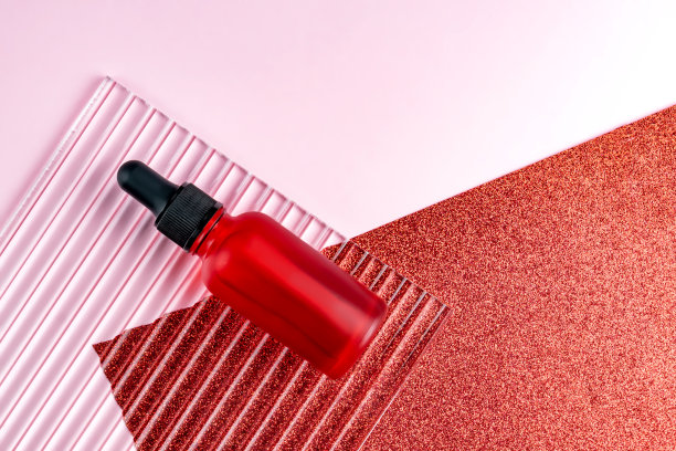 产品照片。模型的脸血清瓶空白标签上的粉红色和闪闪发光的红色背景。美容理念，面部护肤图片下载