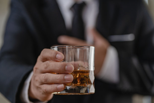 酒保把一杯加冰的威士忌递给男客人。酒吧的其余概念的特写严肃的商人拿着威士忌显示行政特权的概念。图片下载