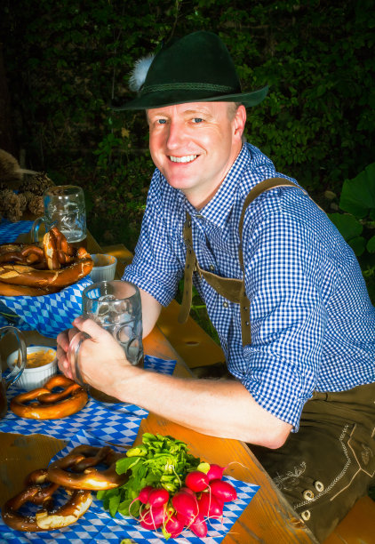 英俊的巴伐利亚人坐在户外的长凳上喝啤酒图片下载