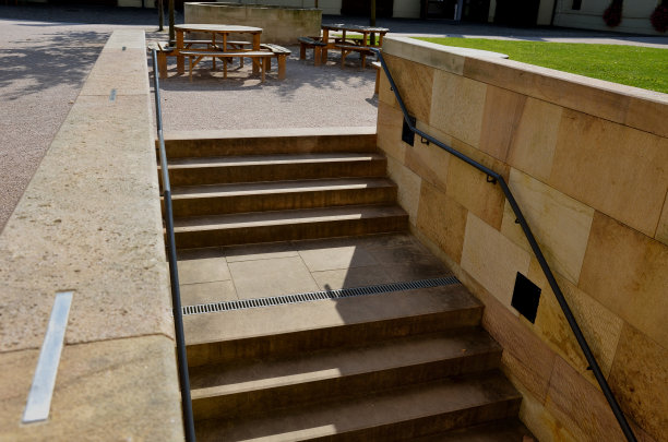 米色楼梯沿着草坪庭院的地形向下延伸，带有公园小径。墙是用采石场的砂岩块加工而成。背光楼梯，两侧有卤素，还有地窖图片下载