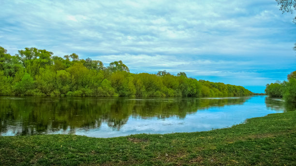 美丽的春天绿色景观，流水和蓬松的云。美丽的大自然在春天。没有人。多云天空下的夏日风景照片。图片下载