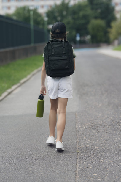 背着背包站在路上的妇女的后视图图片下载