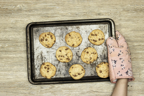 特写手拿着一盘自制的巧克力饼干在木桌上图片下载