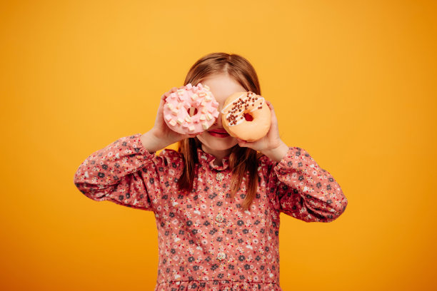 黄色背景下带甜甜圈的女孩图片下载