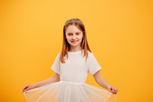 戴着隔离在黄色背景上的王冠的女孩图片下载