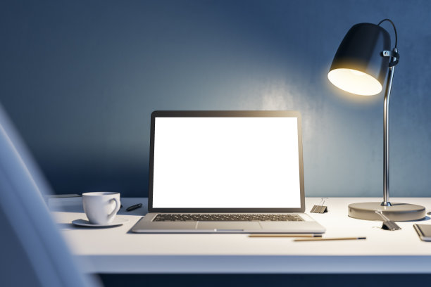 工作概念与前视图空白白色现代笔记本电脑屏幕与空白的地方，白色茶杯和办公工具在灯光桌上被灯照亮在黑暗的墙壁背景。3D渲染，模拟图片下载