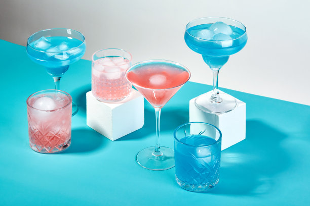 五颜六色的鸡尾酒装在不同形状的玻璃杯里，色彩斑斓的背景加上坚硬的阴影图片下载