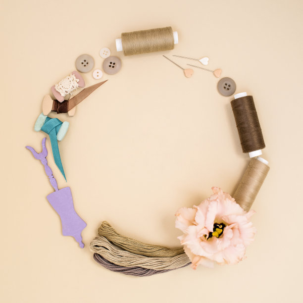 用米色色调的裁剪和缝纫配件和用品制成的花环:别针，纽扣，线轴，花边，木制模特模型。爱好的想法。手工、手工、DIY或艺术的概念。图片下载