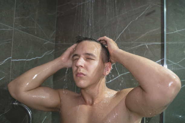 年轻男子洗头发，站在浴室库存照片图片下载