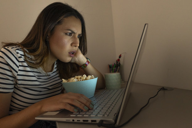 一位拉丁妇女在舒适的家里用笔记本电脑全神贯注地看电视剧图片下载