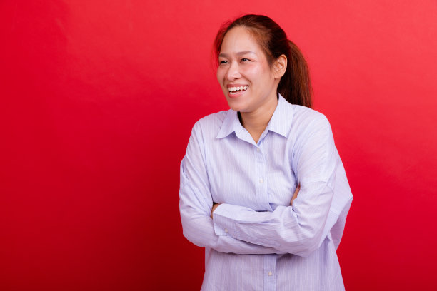 快乐的微笑笑东亚妇女肖像在红色背景。图片下载