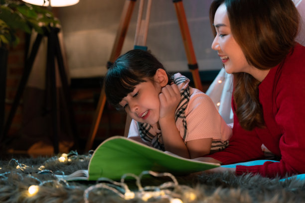 照片上一个小女孩在睡前听故事，那是他的妈妈在育儿室读的图片下载