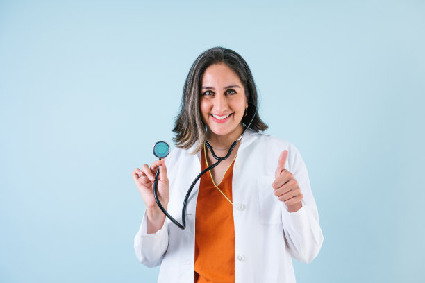 在拉丁美洲的墨西哥，拉丁女医生指着蓝色背景上的空间大笑图片下载