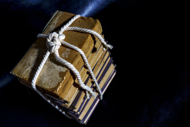 一堆旧书用绳子系在深色的背景上。图片下载