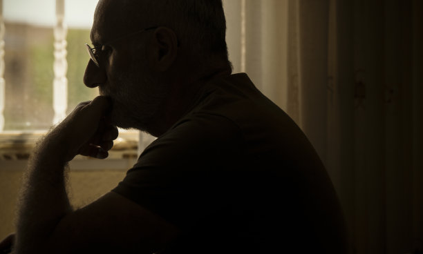 带眼镜的成年男子在房间里使用笔记本电脑的侧视图图片下载