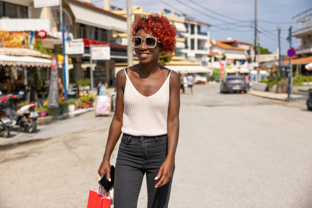 一个年轻的非裔美国妇女，一头染红的卷发，走在街上图片下载