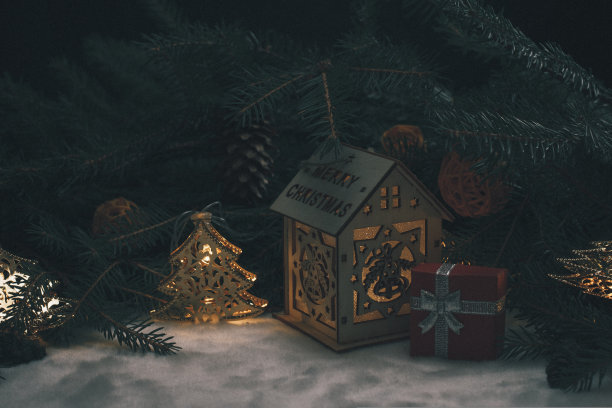 童话般的冬天的照片。在圣诞树的树枝上有一个小木屋，里面有一个装着礼物的小盒子。神奇的圣诞节日气氛。图片下载