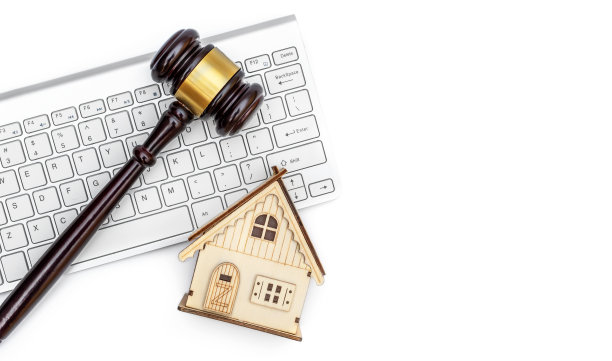 房子的模型与电脑键盘和法官的木槌在白色背景。图片下载