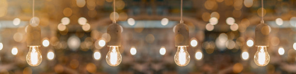 吊坠的浅色混凝土灰色灯泡在混凝土插座上从客厅的天花板上挂下来，带有金色的散景灯图片下载