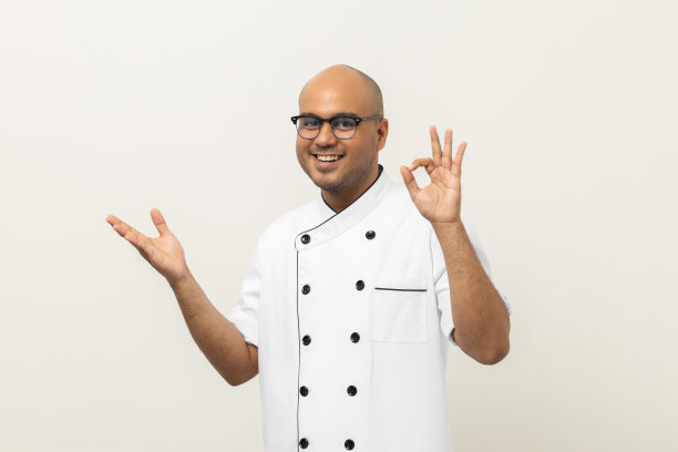 休闲年轻英俊的亚洲男子厨师在制服站各种发帖品尝喜悦美味的手势。烹饪印度人职业厨师或面包师在厨房的人，餐厅和酒店。图片下载