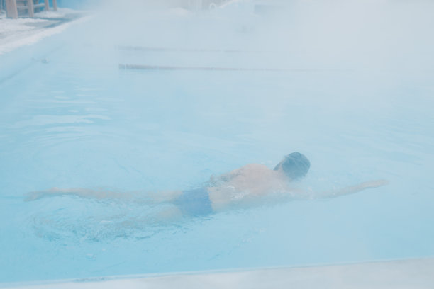 适合游泳的男子训练游泳在开放的冬季游泳池有雾。地热户外温泉概念，图片下载