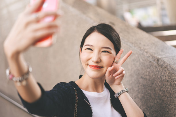 年轻的亚洲商业单身女性的手机自拍。图片下载
