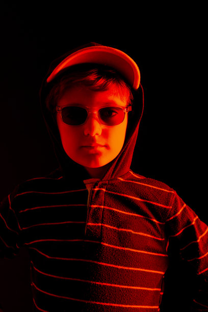 黑色背景的孩子穿着连帽运动衫，帽子和太阳镜。图片下载
