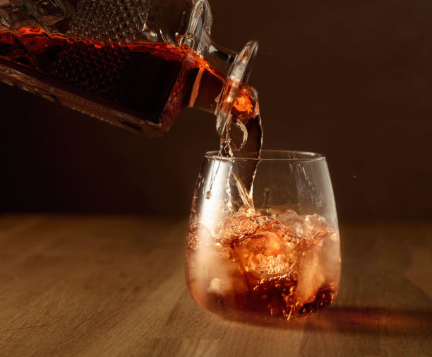 威士忌被倒入加冰的有坝的玻璃杯中。图片下载