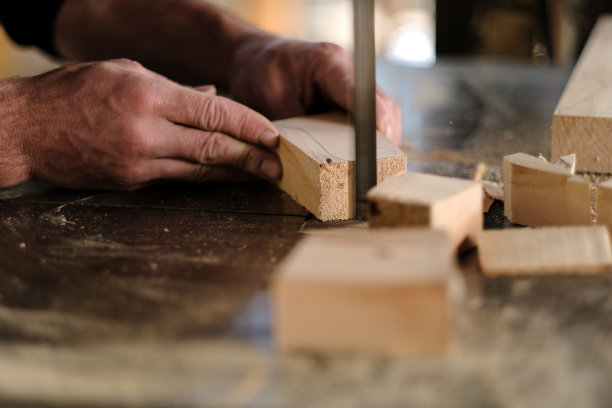 年轻的木匠正在用磨砂机打磨一块木头图片下载