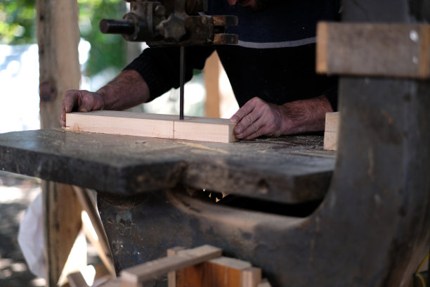 年轻的木匠正在用磨砂机打磨一块木头图片下载