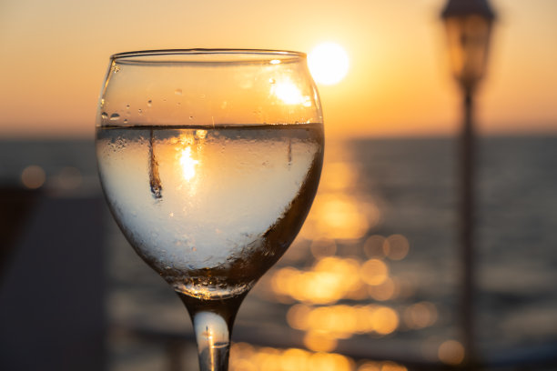 在海边附近的日落时分喝一杯白葡萄酒图片下载