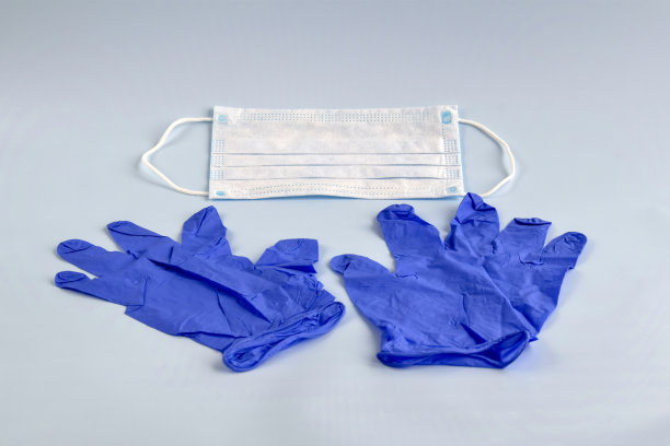 一双薄薄的蓝色医用乳胶手套和浅蓝色背景的面罩。一次性医用橡胶手套和口罩。保护对象。补救措施。特写镜头。有选择性的重点。副本的空间。图片下载
