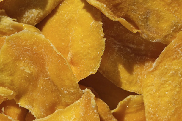 干芒果片特写在一个白色。前视图。特写镜头。芒果芯片背景。脱水脆皮水果片、片。一堆晒干的黄色水果。健康的一餐。俯视图，平铺。图片下载